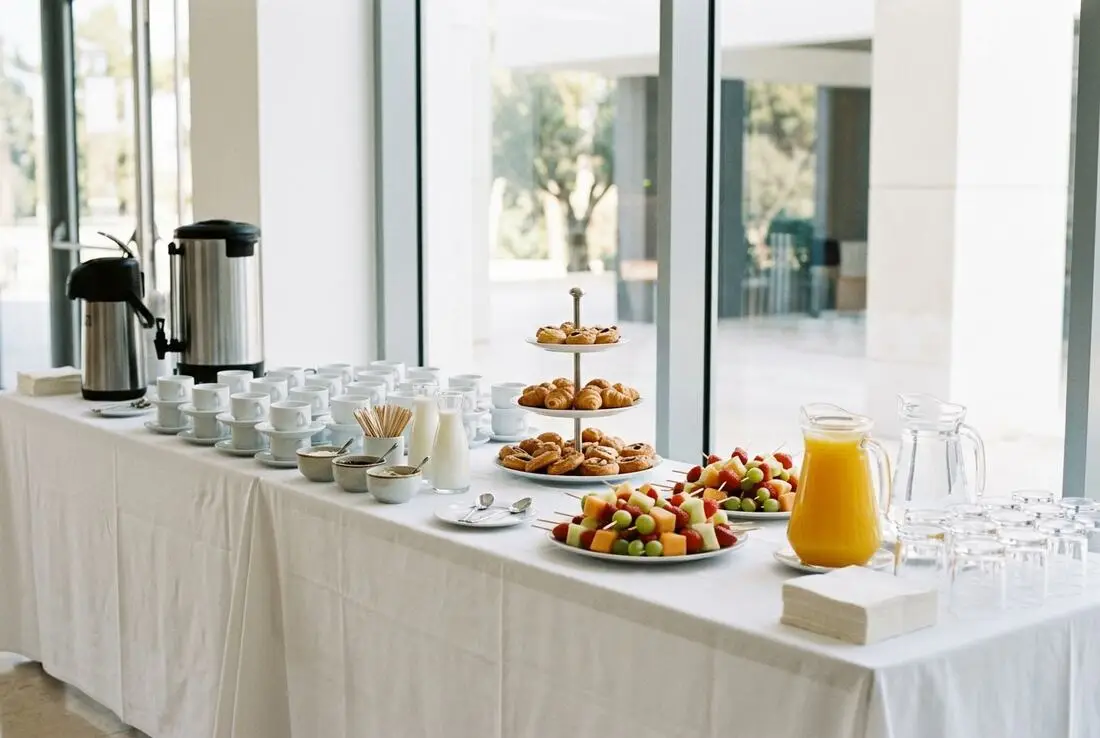 Mesa de coffee break con café, fruta y bollería