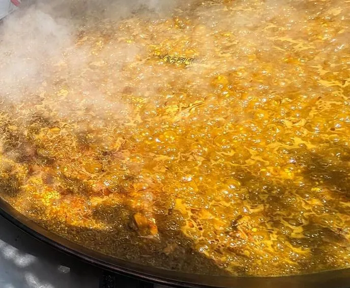 Paella cocinándose entre vapor sobre un quemador