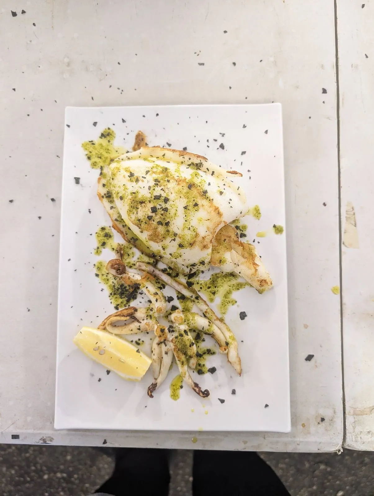 Calamar a la plancha con limón en un plato alargado