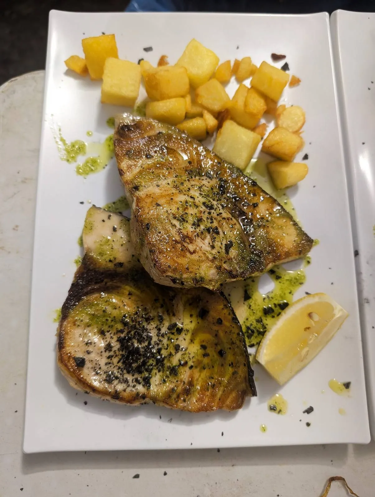 Pescado a la plancha con patatas sobre un plato blanco
